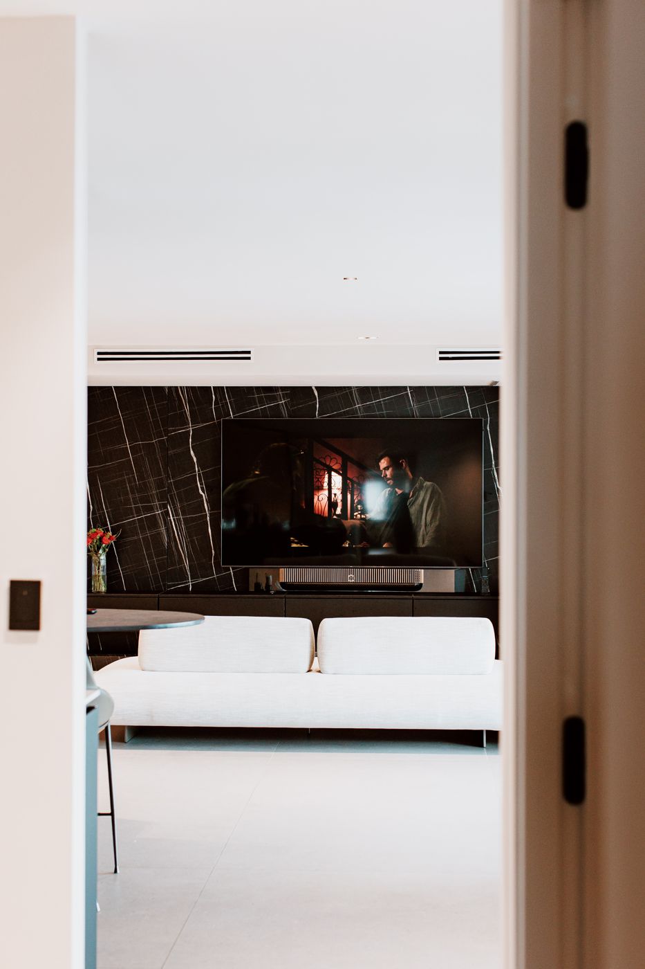 Sala con TV y soundbar integrados en pared de mármol — proyecto AV Design